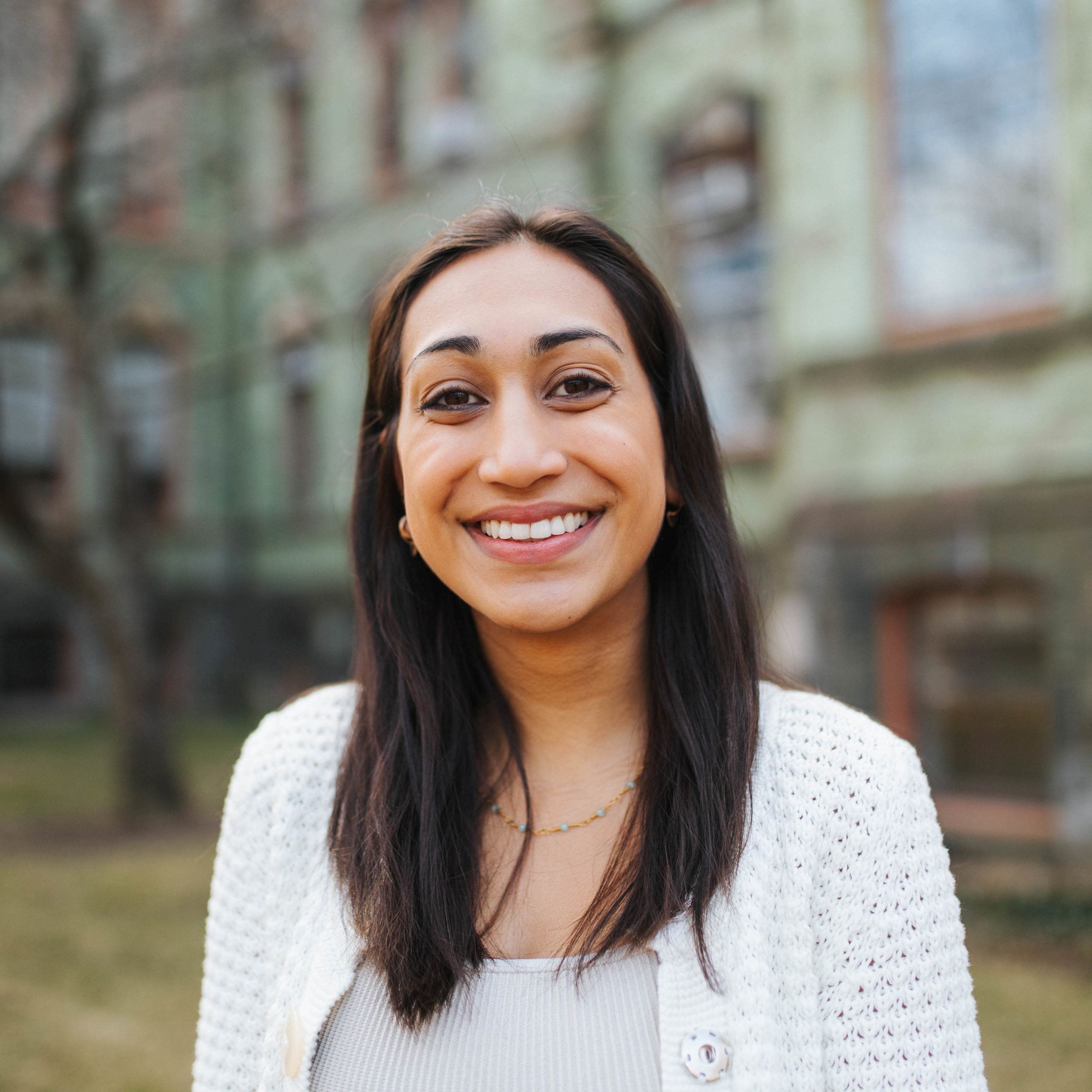 A woman with a wide smile and dark hair wearing a white sweater