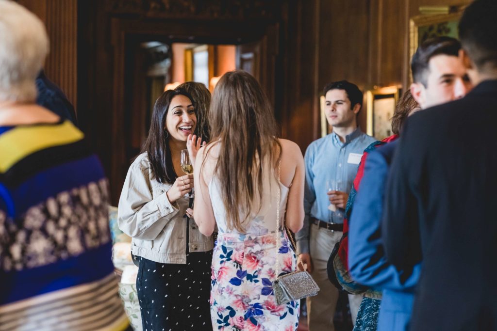 New Thouron Scholars chatting and laughing at the Thouron Award Welcome Party in Philadelphia