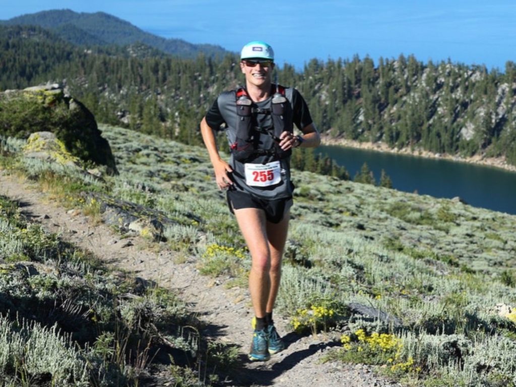 Sam Bennett runs in a black tshirt and shorts wearing sunglasses and a blue baseball cap during a race through the U.S.