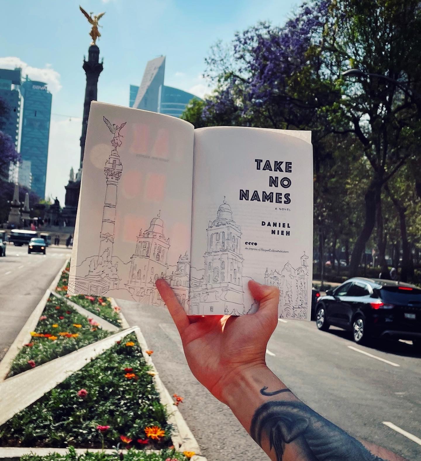 Daniel Nieh holds up an open copy of Take No Names that shows a drawing of the scene in front of him