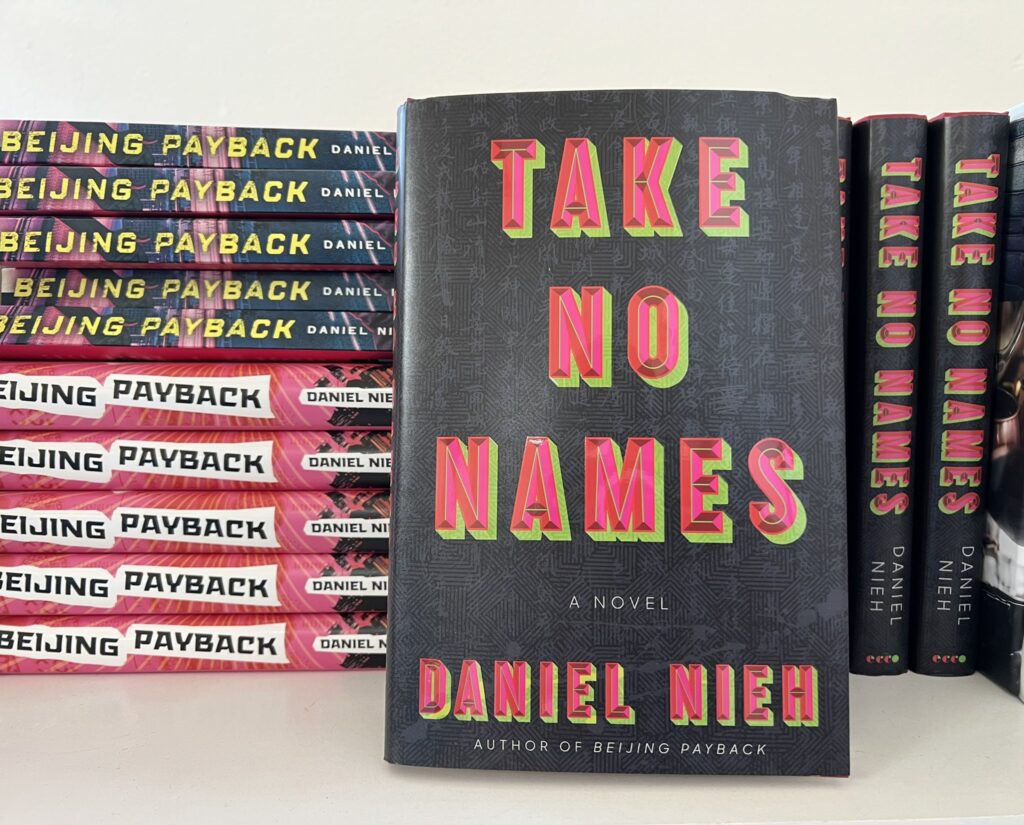 Daniel Nieh's novel Take No Names leans against a stack of other copies of that book and his other novel Beijing Payback