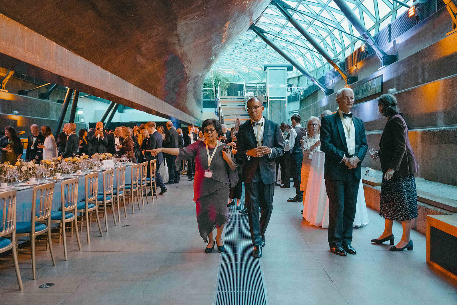 Alumni and Scholars enter the great hall beneath the Cutty Sark and look for their seats.