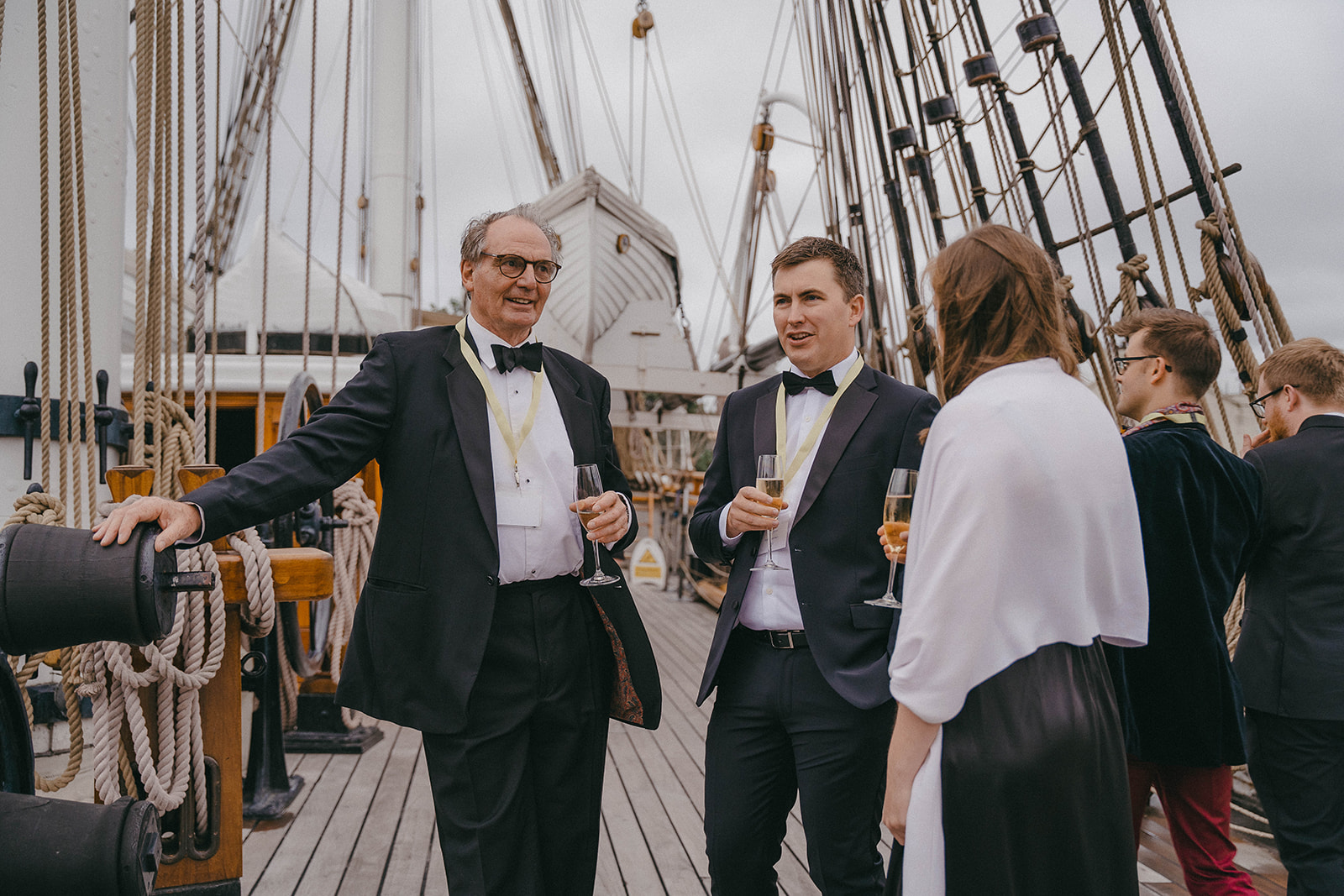 Alumni chat amongst themselves on the deck of the Cutty Sark with champagne in hand.
